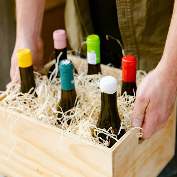 A wooden case of six wines being carried at Cave
