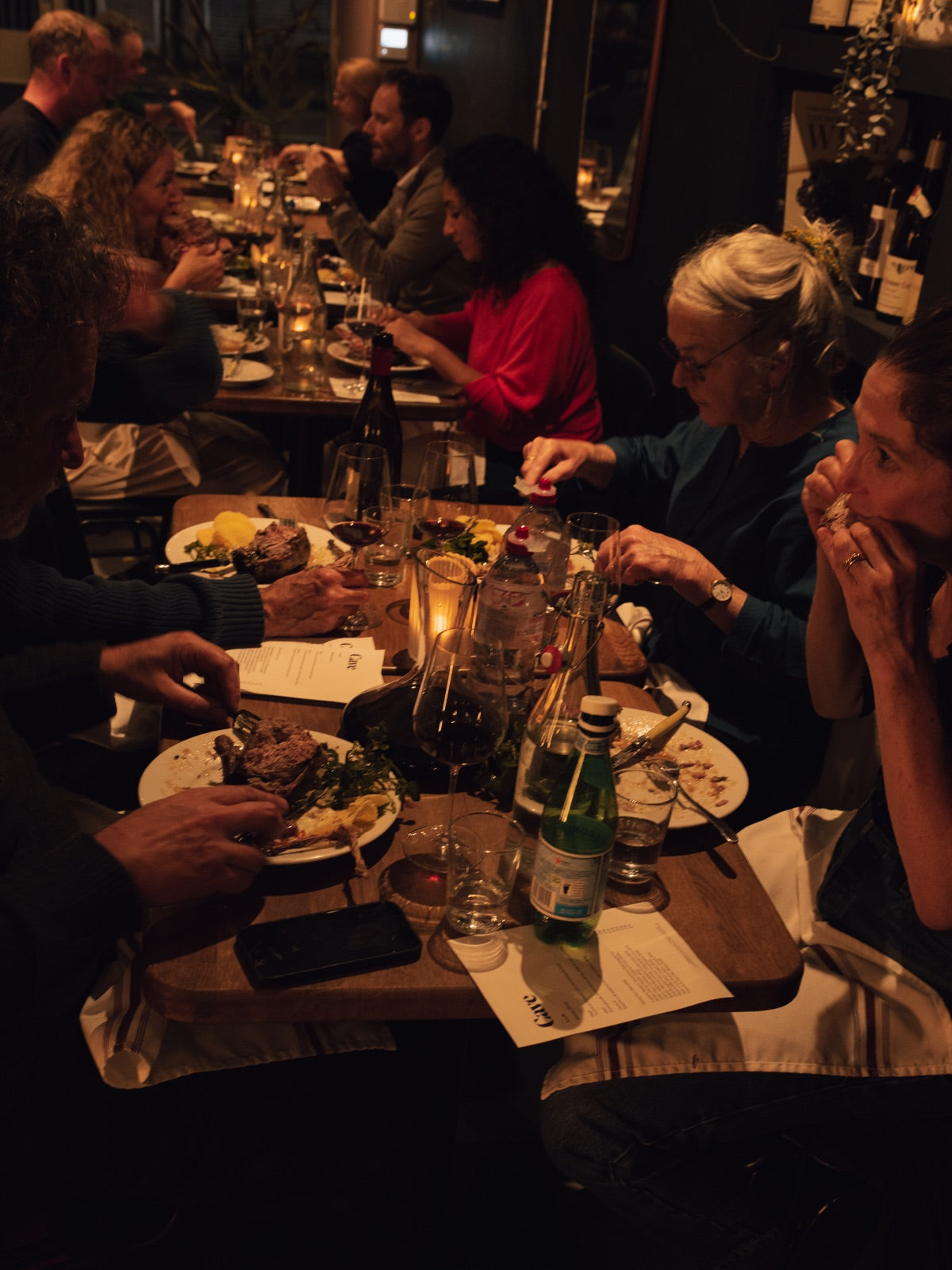 Guests enjoying dinner and wine around candlelit tables at Cave